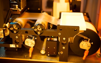 Photo of a plastic substrate moving over two rollers for nano-sculpting.